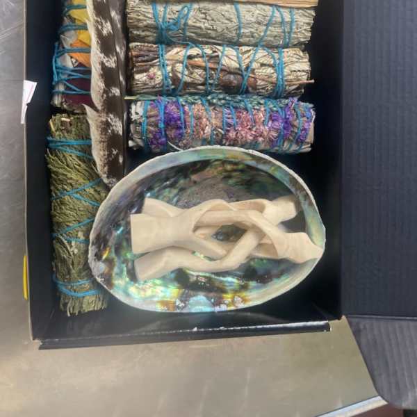 Box of bundled sage, feathers, and an abalone shell with ribbon