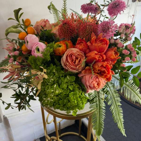 Mixed bouquet with orange and pink flowers in a gold stand