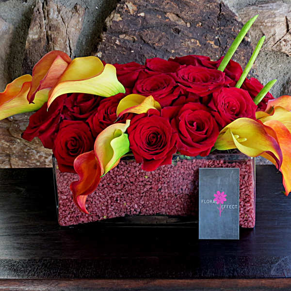 Red roses and orange-yellow calla lilies in a rectangular vase