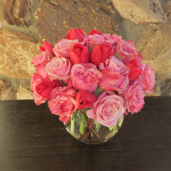 Pink and red roses arranged in a clear glass vase