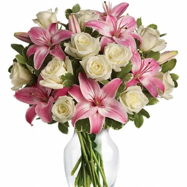 Pink lilies and white roses arranged in a clear glass vase