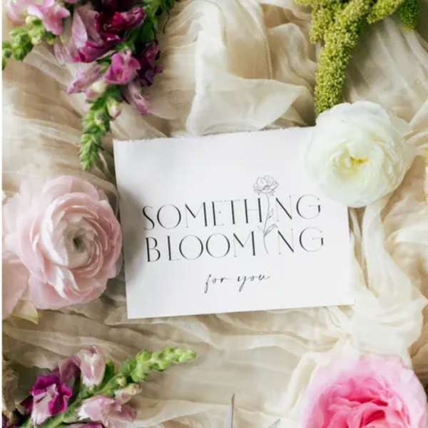 Floral arrangement with pink and white blooms around a card reading "Something Blooming for you"