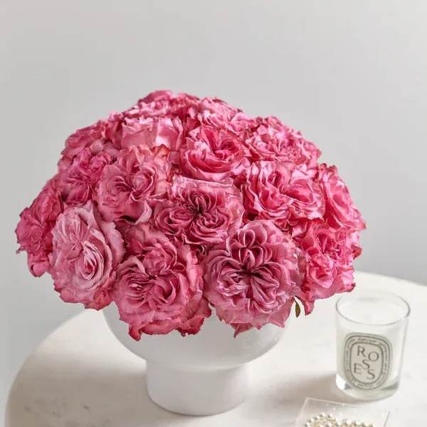 Pink rose bouquet in a white vase on a round table