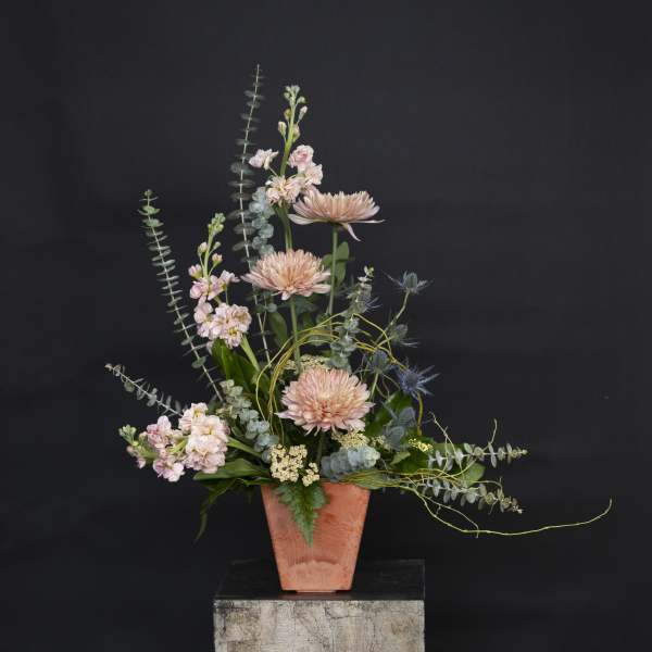 Tall pastel floral arrangement in a terracotta vase