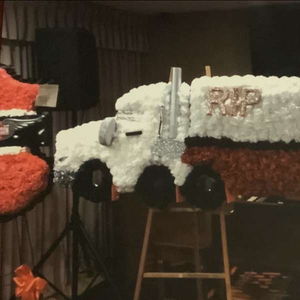 Floral casket spray shaped like a truck with "RIP COOP" lettering