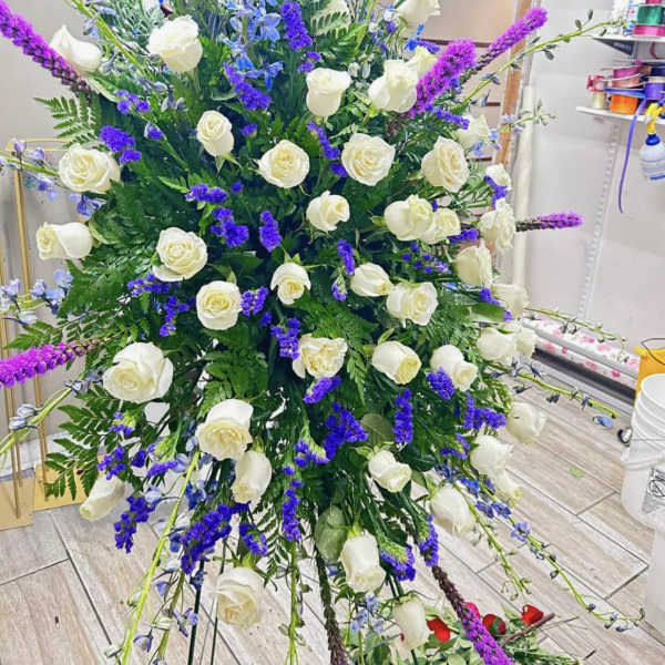 Large standing floral spray with white roses and purple-blue accents