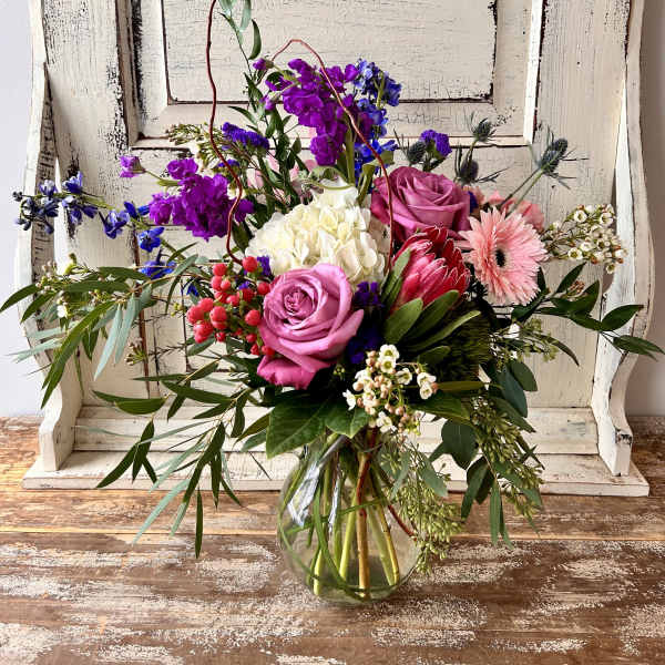 Mixed bouquet in a clear glass vase with pink, purple, white, and blue flowers