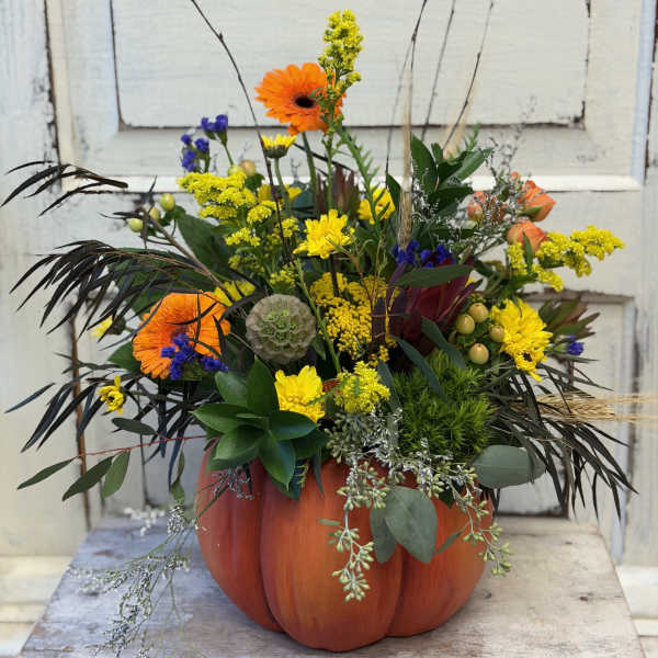 Mixed orange and yellow flowers arranged in a pumpkin-shaped container