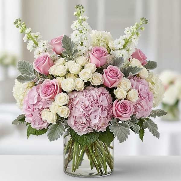 Pink and white roses with hydrangeas in a clear glass vase