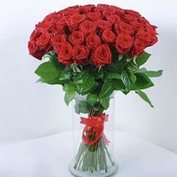 Bouquet of red roses in a clear glass vase with a red ribbon