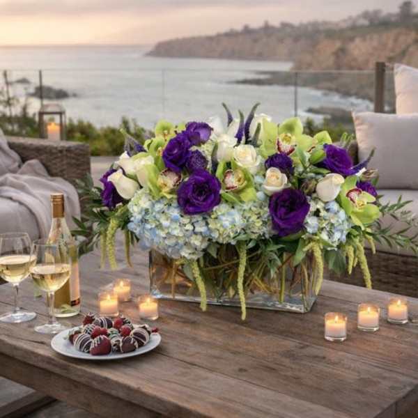 Purple and white floral centerpiece on a table with candles and wine glasses