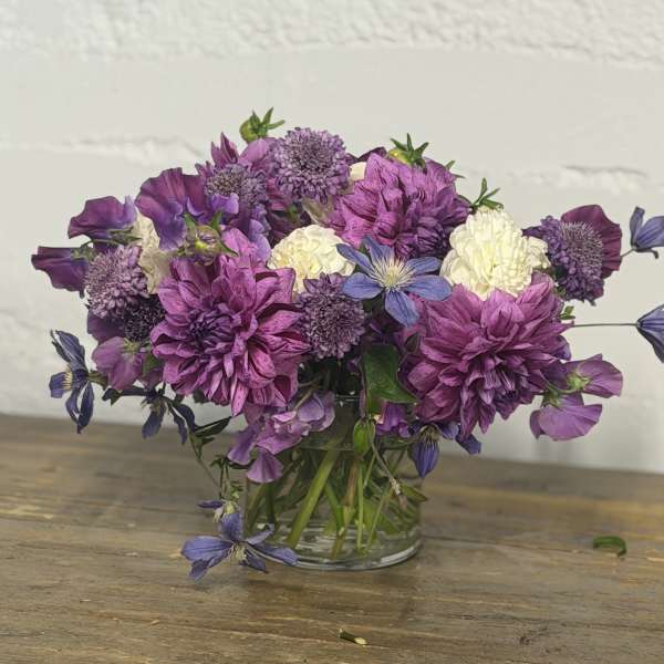 Purple and white mixed bouquet in a clear glass vase