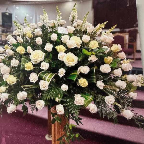Large arrangement of white and pale yellow roses in a tall vase