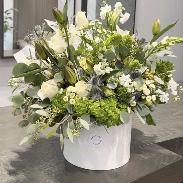 White and green floral arrangement in a white hat box