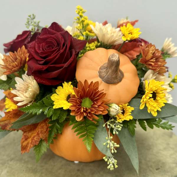 Fall floral arrangement with a pumpkin and red rose