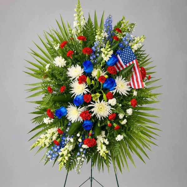 Standing floral wreath with red, white, and blue flowers and an American flag