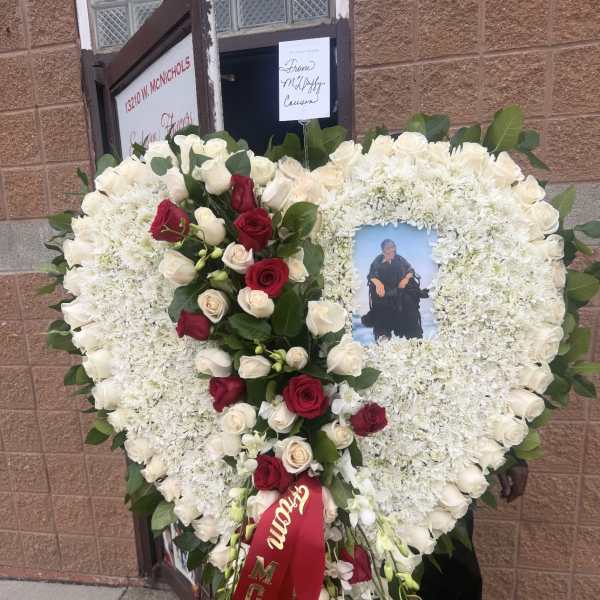 Heart-shaped funeral wreath of white and red roses with a photo center