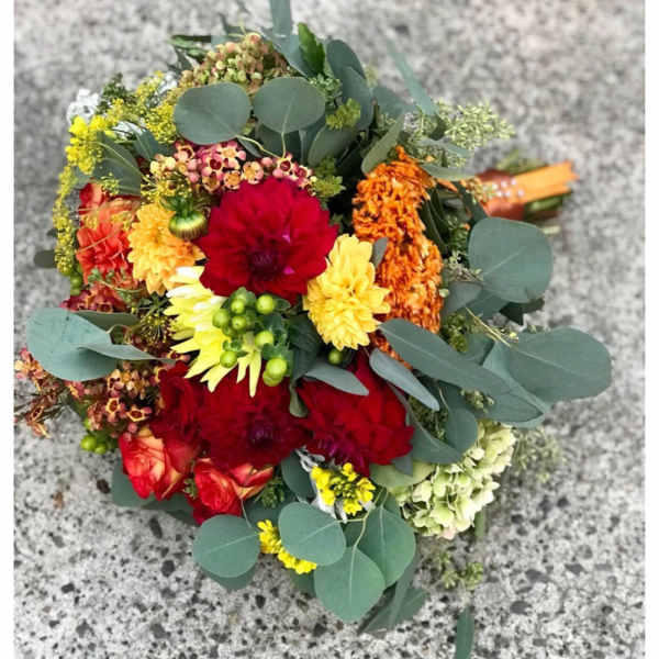 Mixed bouquet of red, yellow, orange, and green flowers with eucalyptus