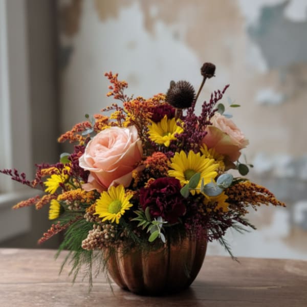 Mixed bouquet of roses and yellow daisies in a copper pumpkin vase