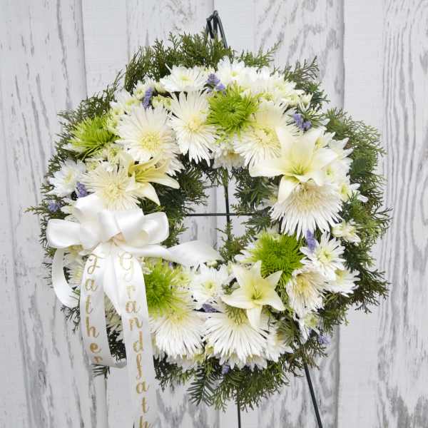White floral wreath with a ribbon on a stand
