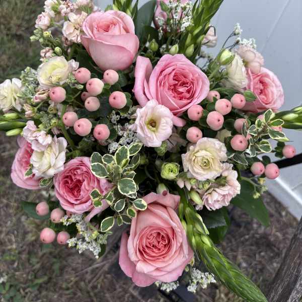 Pink roses and mixed blooms arranged in a hand-tied bouquet