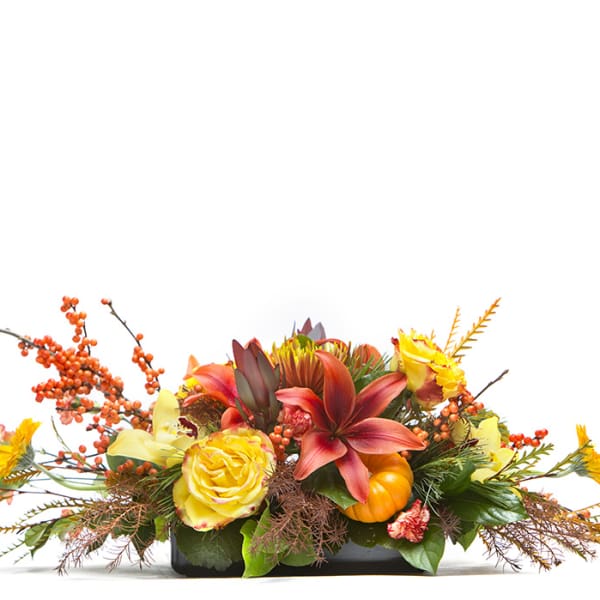 Low floral arrangement with yellow roses, orange lilies, and autumn berries in a black container