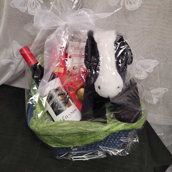 Gift basket with wine, chocolates, and a plush dog in clear wrap