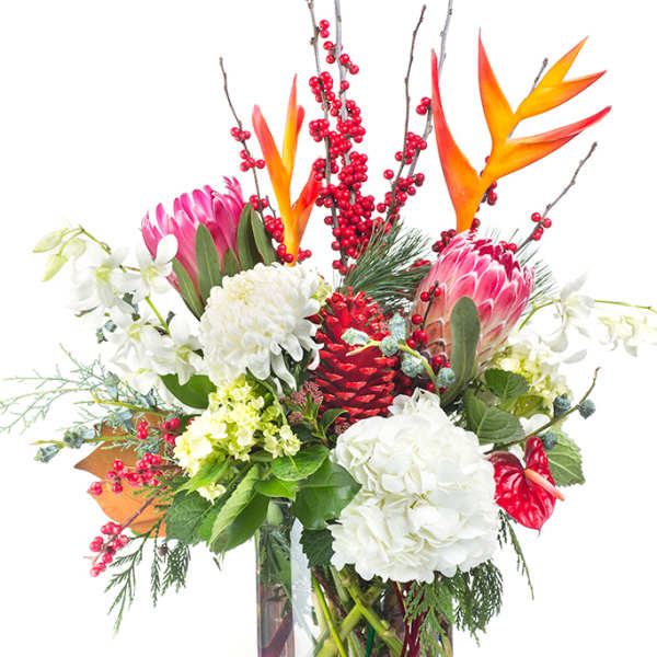 Tropical bouquet with pink protea, white hydrangeas, and red berries in a glass vase