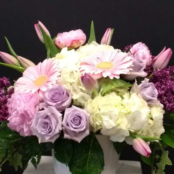 Pink and lavender flowers arranged in a white pot
