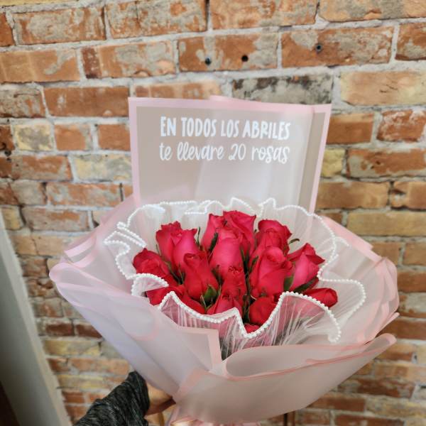 Bouquet of red roses wrapped in pink paper with a note card