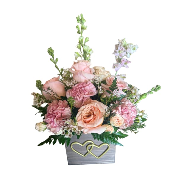 Pink and peach floral arrangement in a gray box with gold hearts
