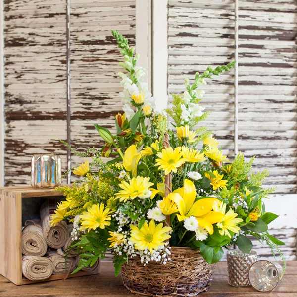 Yellow lilies and daisies arranged in a woven basket