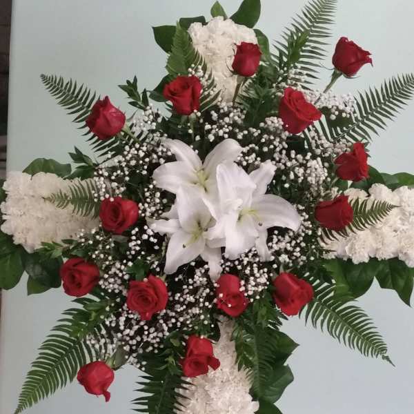 Cross-shaped floral tribute with red roses and white lilies