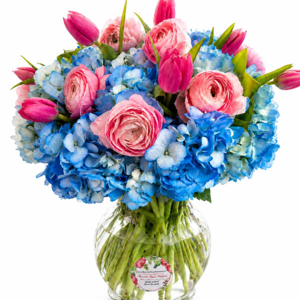 Pink tulips and blue hydrangeas arranged in a clear glass vase
