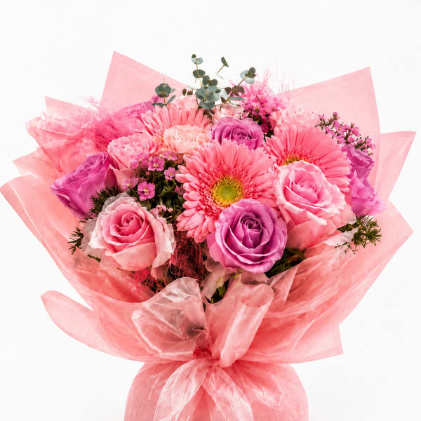 Pink and purple bouquet of roses and gerbera daisies wrapped in pink paper