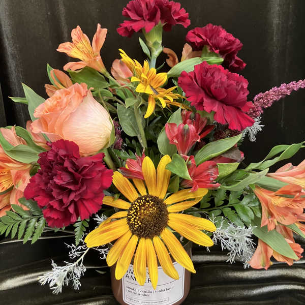 Mixed bouquet with a sunflower, carnations, and alstroemeria in a candle jar