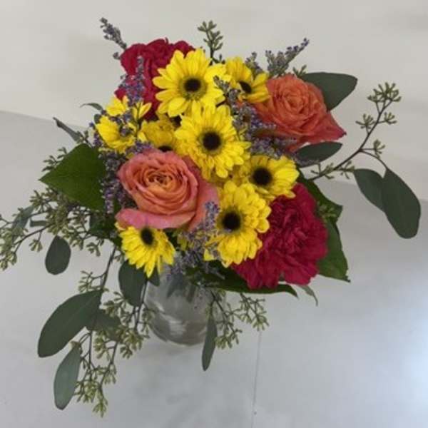 Bouquet of yellow daisies and pink roses in a clear vase