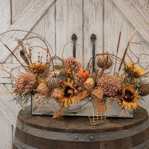 Autumn floral arrangement in a rectangular glass vase with pumpkins and sunflowers
