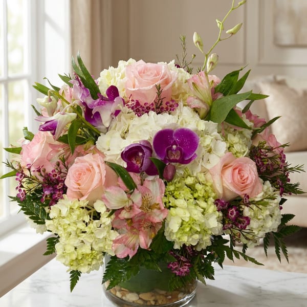 Pink roses and purple orchids arranged in a glass vase