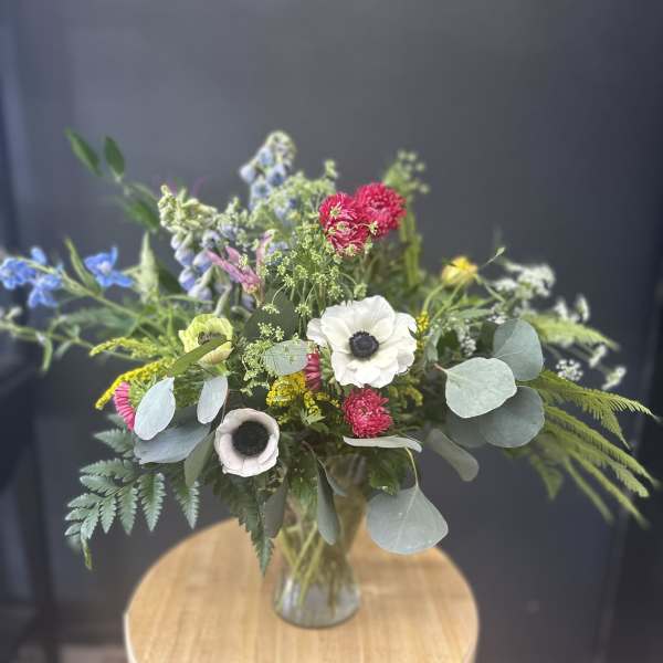 Mixed bouquet in a glass vase with white, pink, blue, and yellow flowers
