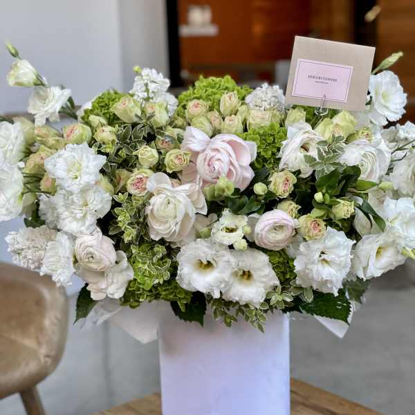 Large white and pale pink flower arrangement in a white box