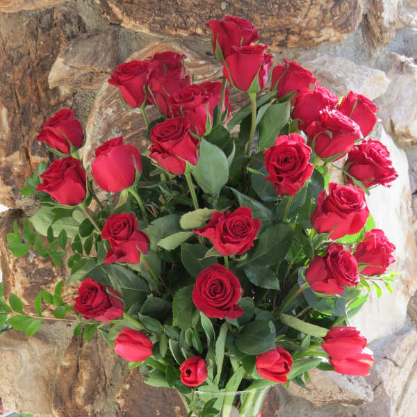 Bouquet of red roses in a clear glass vase with a red ribbon