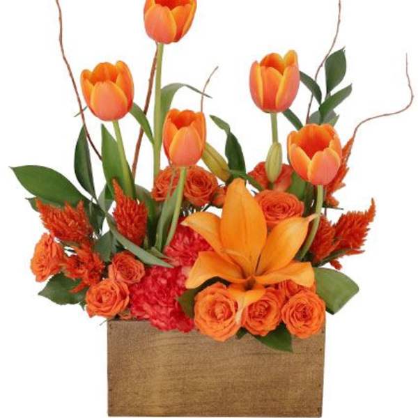 Orange tulips and roses arranged in a wooden box