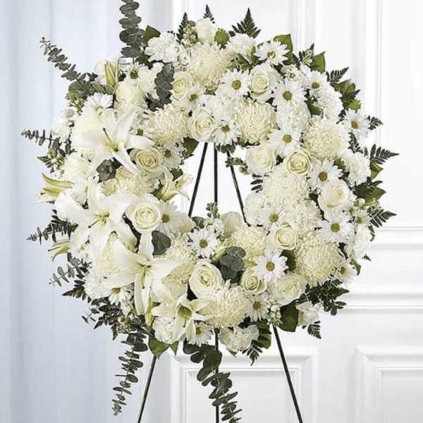 White floral funeral wreath on a black stand