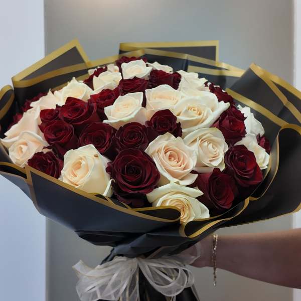 Bouquet of red and white roses wrapped in black paper with gold trim