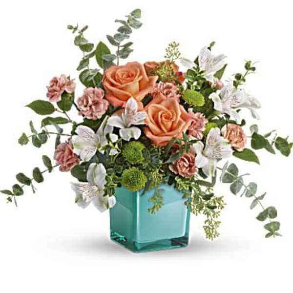 Peach roses and white lilies in a turquoise glass vase
