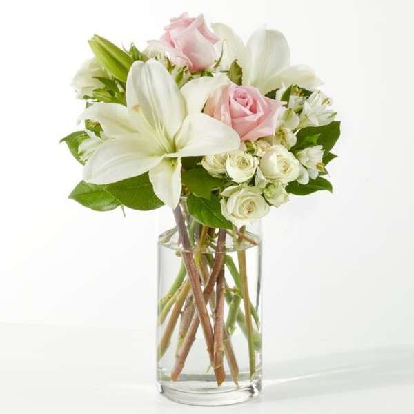Bouquet of white lilies and pale pink roses in a clear glass vase