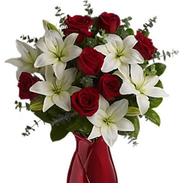 Red roses and white lilies in a red glass vase