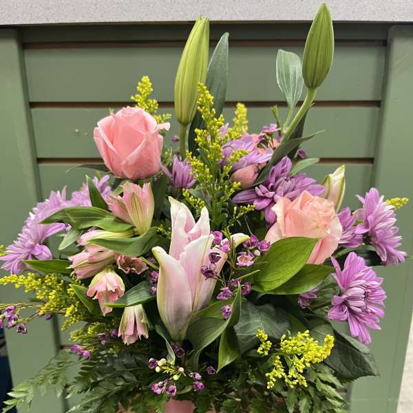 Pink roses and lilies in a pink vase with purple flowers