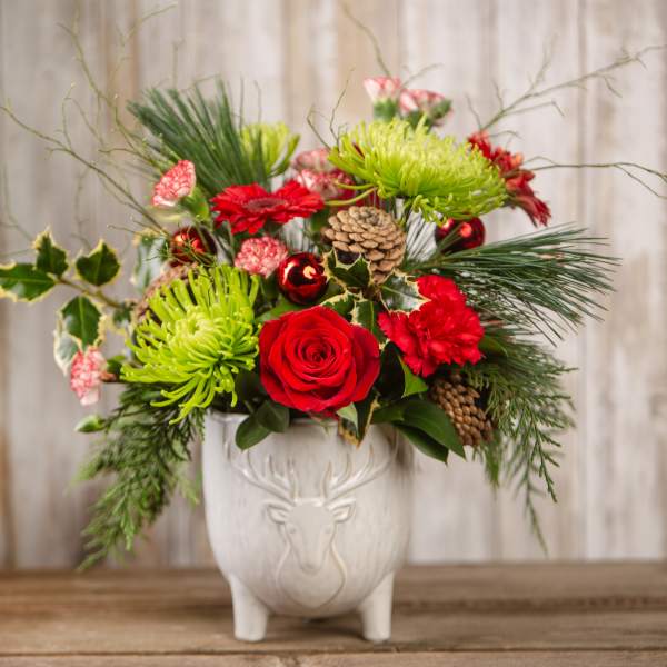 Holiday bouquet with red roses and green chrysanthemums in a white deer vase